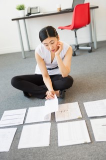 Businesswoman organizing paperwork on floor.