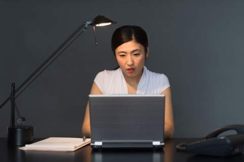 Businesswoman working on laptop at night.