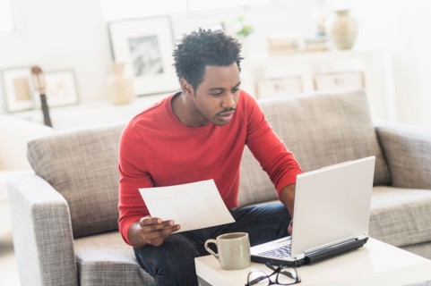 Man sitting on sofa and using laptop.