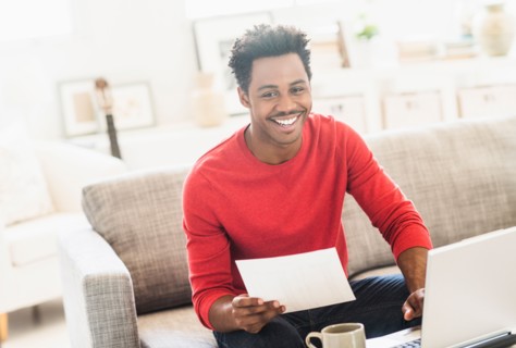 Man sitting on sofa and using laptop.