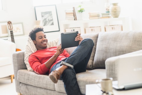 Man lying on sofa and using tablet PC.