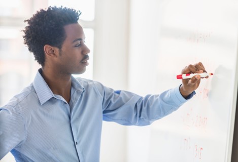 Businessman writing on whiteboard.