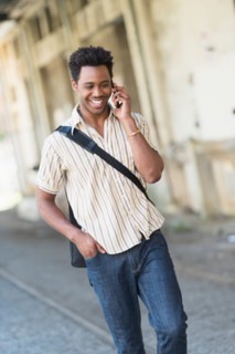 Man walking on street and talking on cell phone.