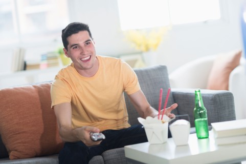 Man eating take out meal and watching television.