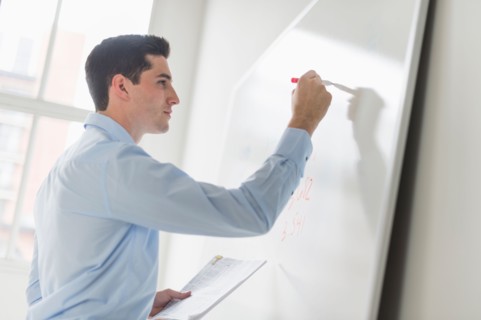 Businessman writing on whiteboard.
