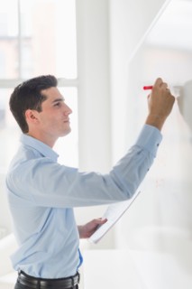 Businessman writing on whiteboard.