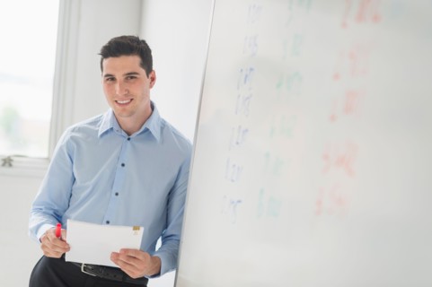 Businessman standing next to whiteboard.