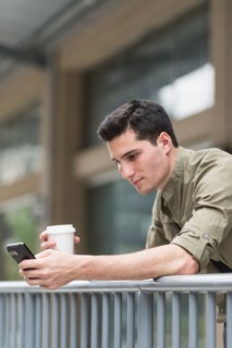 Man drinking coffee and text messaging.
