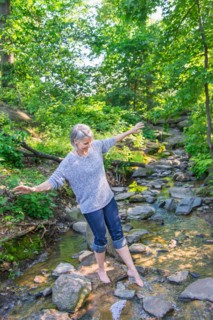 Central Park, New York City. Senior woman crossing stream.