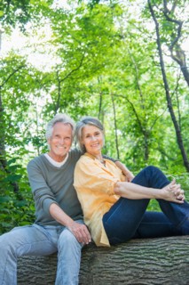Central Park, New York City. Senior couple sitting on log in forest.