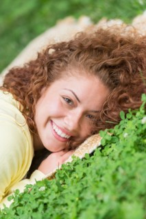 Portrait of young woman lying on grass in park.
