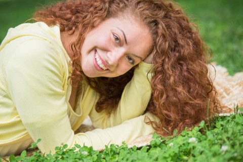 Woman lying on grass in park.