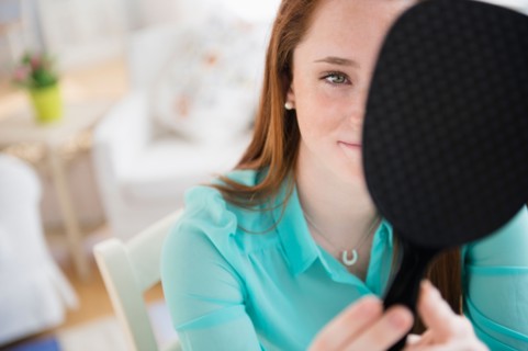 Teenage girl (14-15) with hand mirror