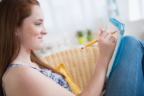 Teenage girl (14-15) writing in notebook