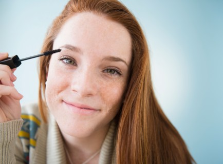 Teenage girl (14-15) applying mascara, studio shot