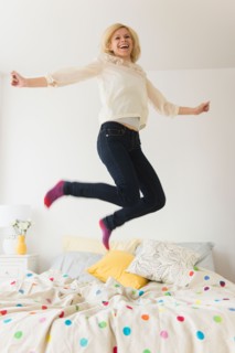Young woman jumping on bed