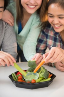 Young women and man eating fresh veggies
