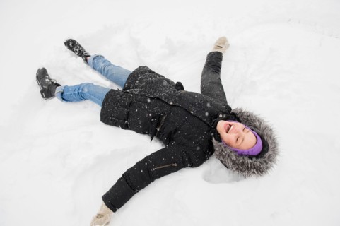 Young woman making snow angel
