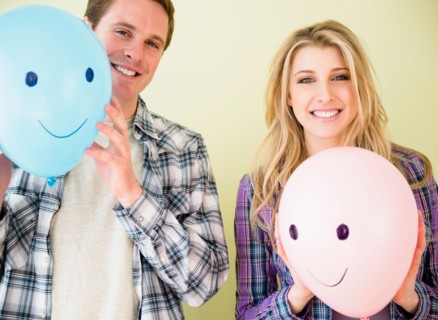 Studio shot of couple holding balloons with smiley faces