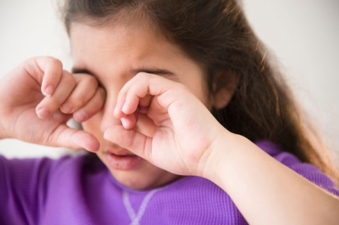 Girl (8-9) crying and covering eyes
