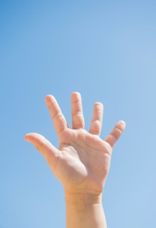 Girl's (8-9) palm against blue sky