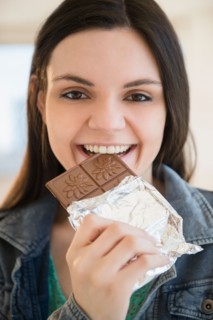 Young woman eating bar of chocolate