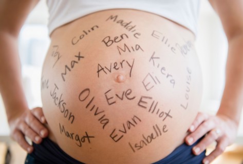 Mid section of pregnant woman with names written on her belly