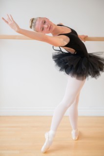 Portrait of teenage (16-17) ballet dancer practicing at barre