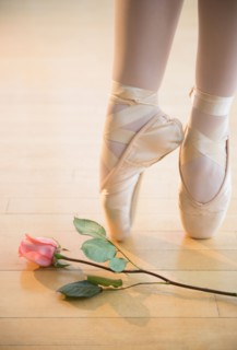 Low section of ballet dancer (16-17) tiptoing next to rose