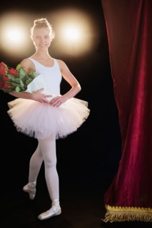 Teenage (16-17) ballerina on stage holding bunch of roses