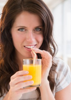 Portrait of young woman holding glass of orange juice