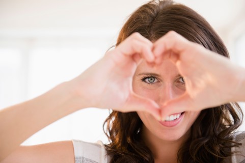 Portrait of young woman making heart shape with her hands