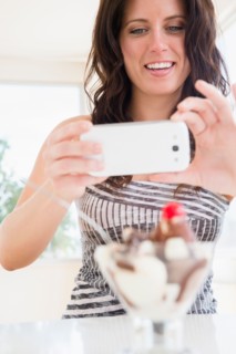 Portrait of woman photographing ice cream sundae