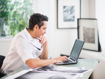 Portrait of man in his photography studio using laptop