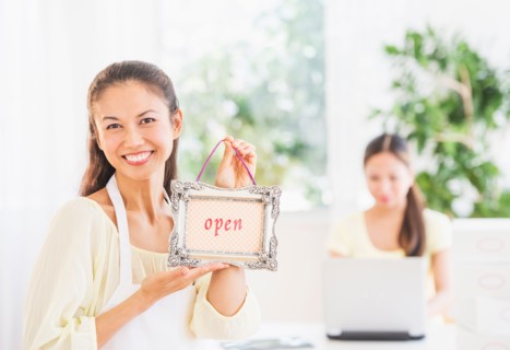 Portrait of mid adult women holding open sign