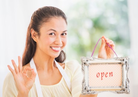 Portrait of mid adult women holding open sign