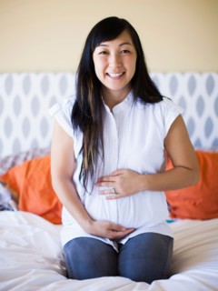 Portrait of pregnant woman sitting on bed