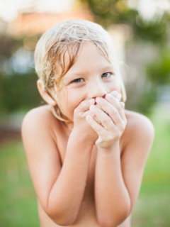 Portrait of boy (8-9) with hands covering mouth
