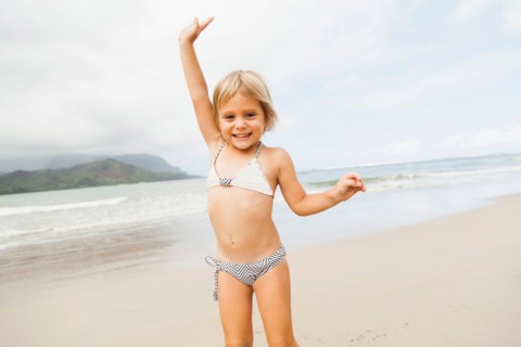 Smiling girl (2-3) on sandy beach