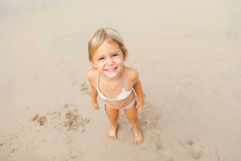 Smiling girl (2-3) on sandy beach