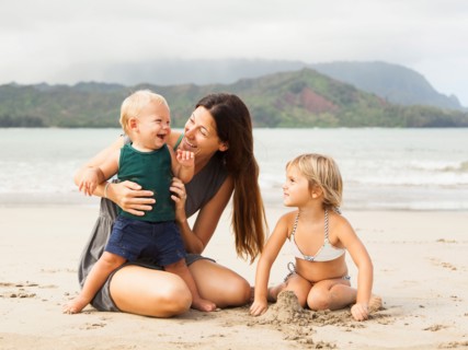 Mother playing with daughters (6-11 months, 2-3) on beach