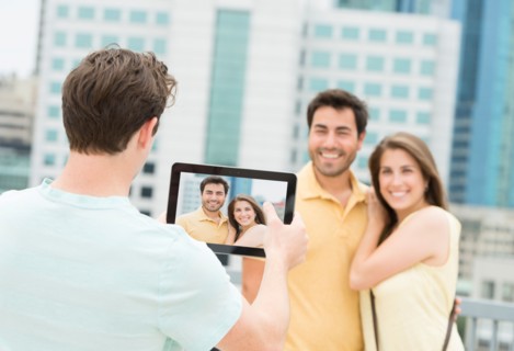 Man using tablet pc to take picture of friends.