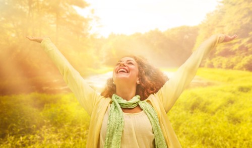 Woman reaching up to sunrays.