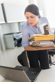 Business woman holding stack of documents and coffee cup.