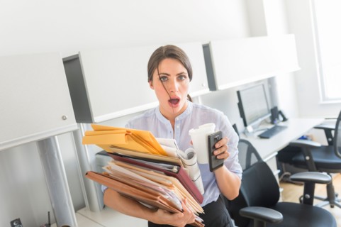 Business woman holding stack of documents in office.