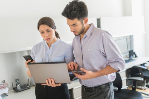 Businessman and businesswoman using technology in office.