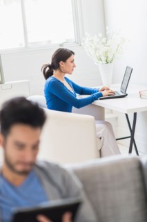 Woman using laptop and man using digital tablet at home.