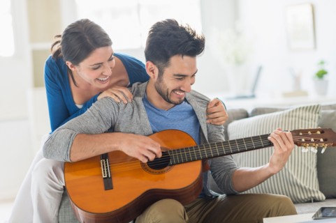 Man playing guitar while woman embracing him.