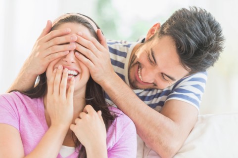 Man covering woman's eyes with his hands.