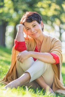Mature woman sitting on grass in park.